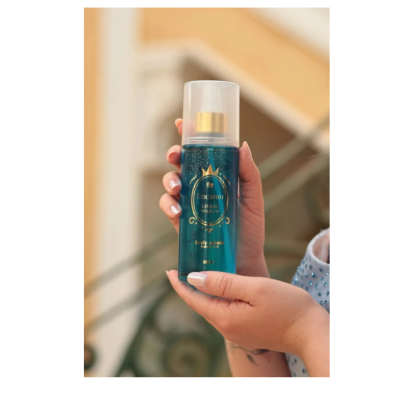 Frasco azul de body splash com tampa transparente segurado por mãos femininas