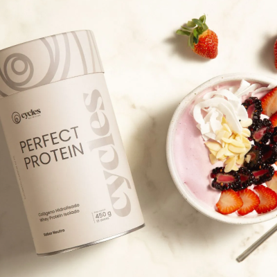 Embalagem de proteína Cycles Perfect Protein junto a tigela de iogurte rosa com frutas e amêndoas.