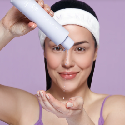 Mulher a espremer líquido de frasco lavanda para a mão, usando faixa branca MSKIN na cabeça