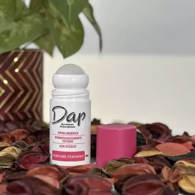 Desodorizante antiperspirante Dap branco com tampa rosa entre folhas decorativas