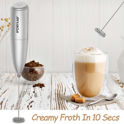 Espumador de leite elétrico prateado POWSAIF ao lado de copo com café com espuma e açúcar em cubos