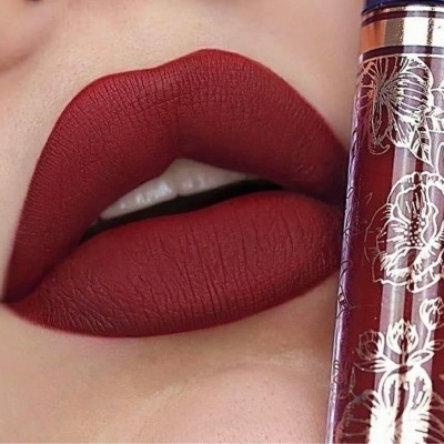 Lábios com batom vermelho matte e frasco de batom líquido com padrão floral
