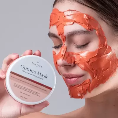 Mulher com máscara facial laranja segurando pote de máscara Outono Mask.