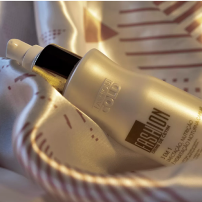 Frasco de creme branco fosco com tampa preta e spray branco sobre tecido claro com padrão