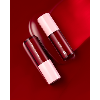 Duas embalagens de batom líquido com tampa rosa sobre fundo vermelho brilhante.