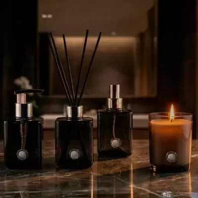 Conjunto de produtos de casa de banho em vidro preto e prata com vela acesa