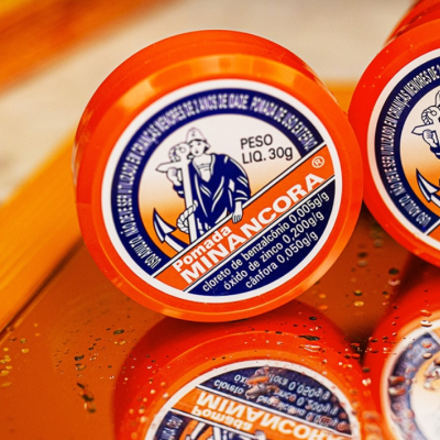 Frasco de pomada Mina Âncora com tampa laranja e etiqueta colorida
