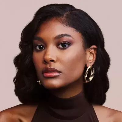 Mulher com brincos dourados de argola e blusa castanha escura