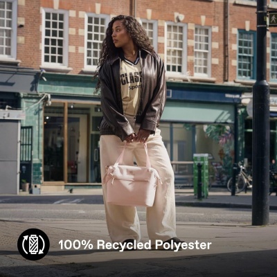 Mala de mão rosa clara segurada por mulher em ambiente urbano