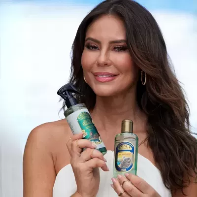 Mulher segurando frascos de produtos Coala com cabelo castanho e top branco