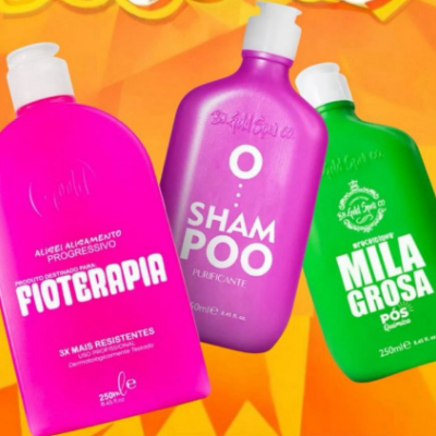 Produtos de cabelo com embalagens rosa, roxa e verde sobre fundo amarelo e laranja
