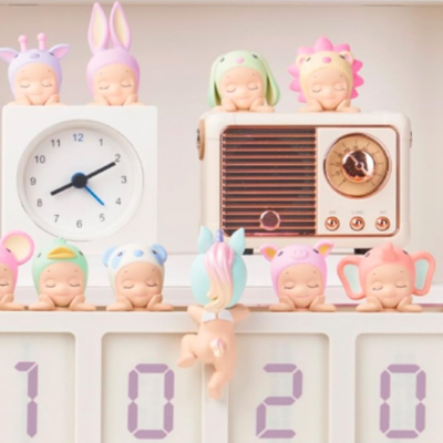 Figuras decorativas de bebés com fatos de animais junto a um relógio branco e rádio bege retro