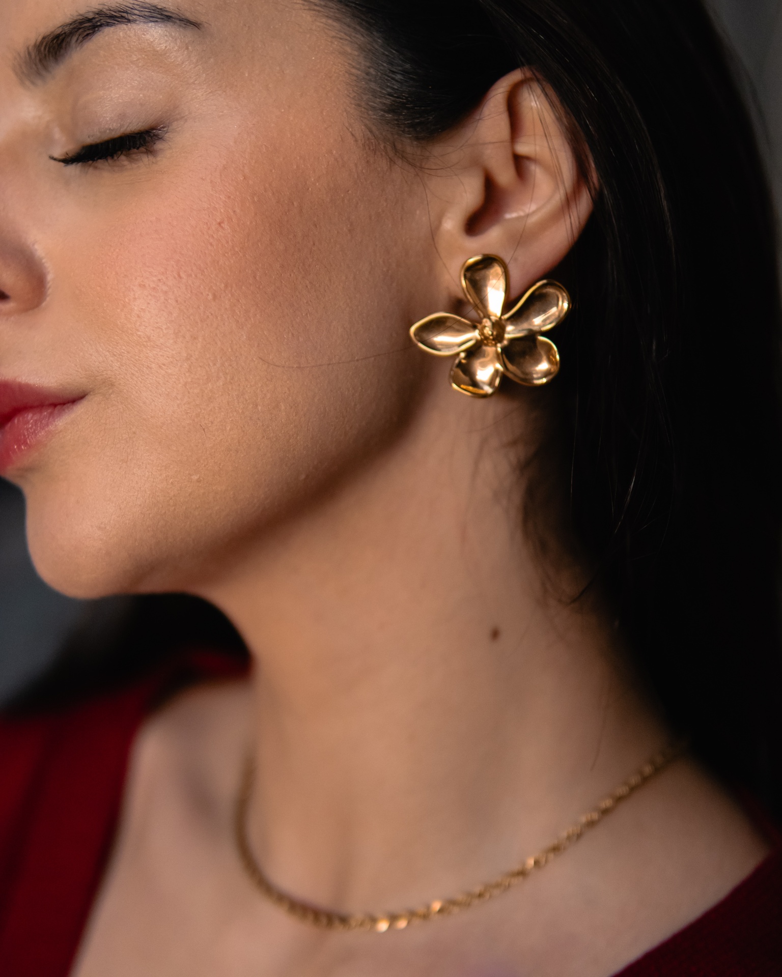 Brincos dourados em forma de flor num rosto feminino