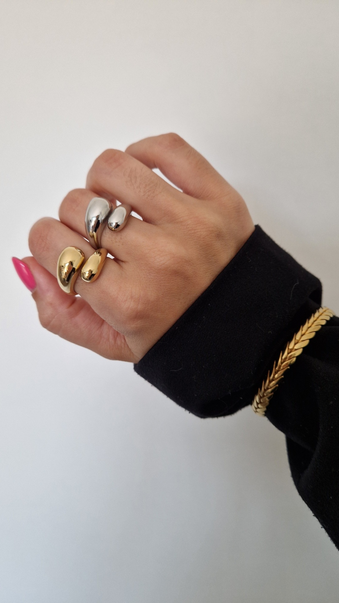 Mão com dois anéis metálicos e pulseira dourada