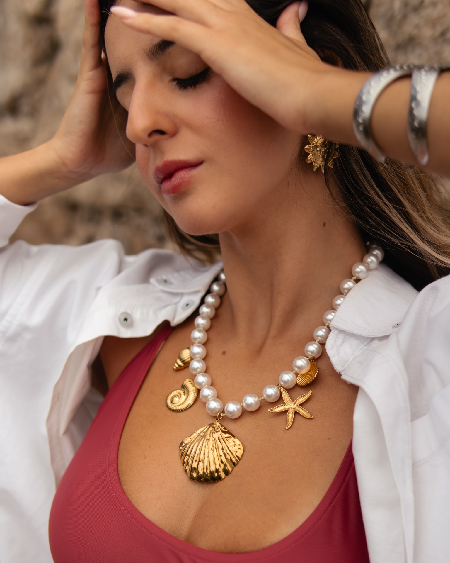 Mulher com colar de pérolas e pingentes dourados marinhos