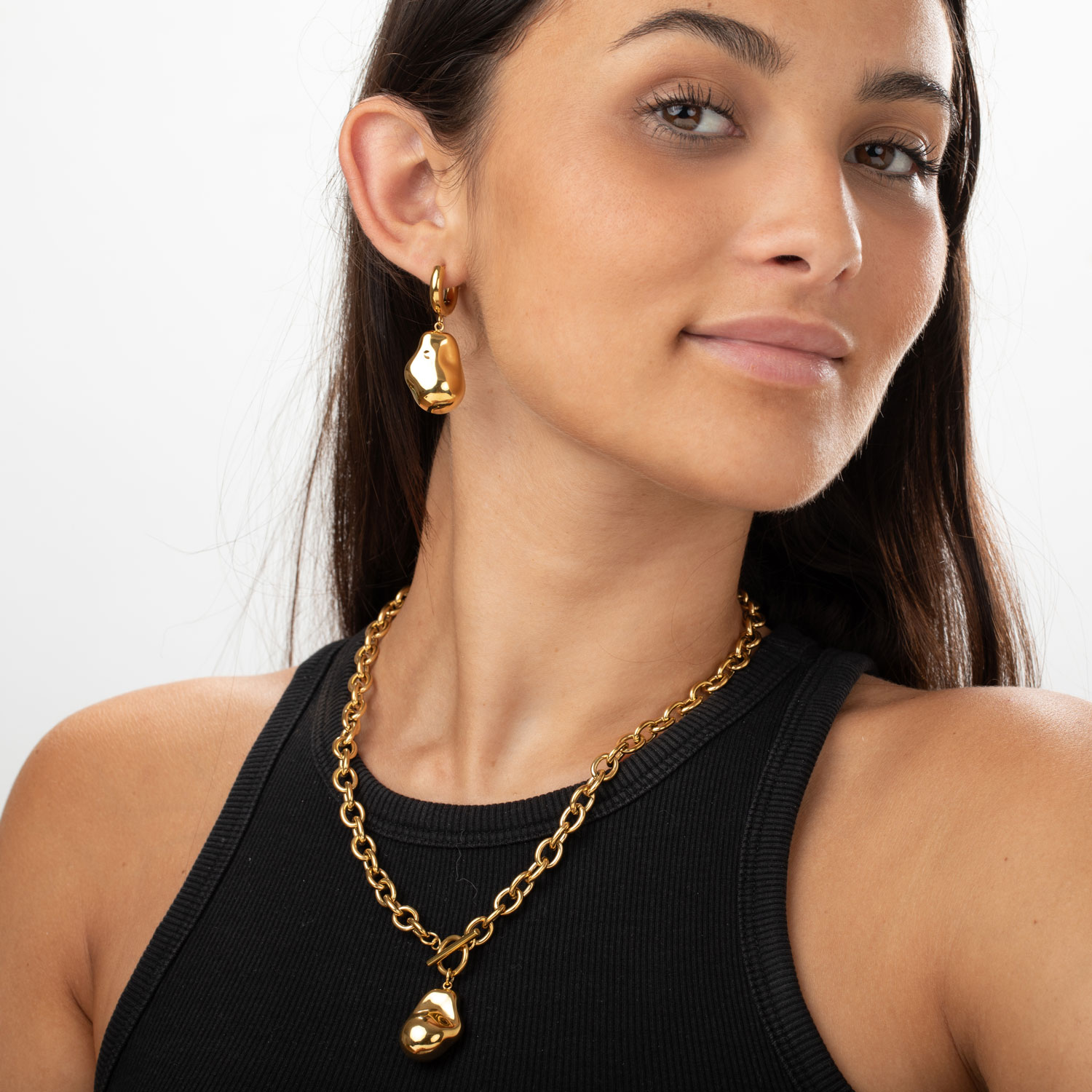 Colar e brincos dourados de metal com pendentes irregulares em mulher com top preto