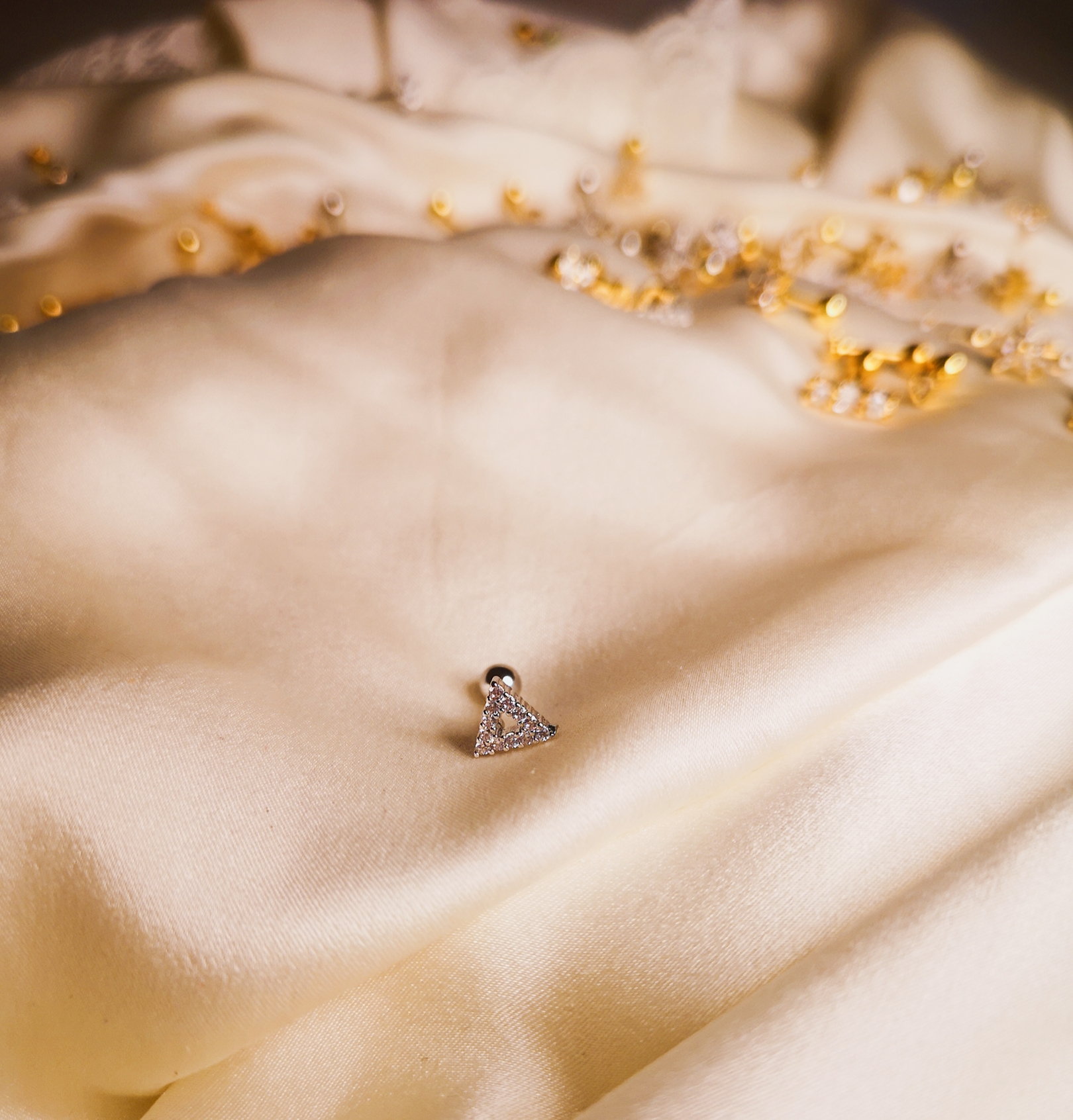 Brincos triangulares com pedras sobre tecido creme