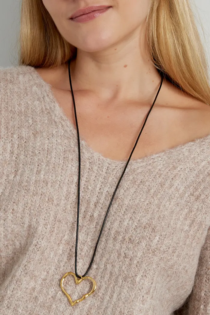Colar com coração dourado e cordão preto em pescoço com suéter castanho claro