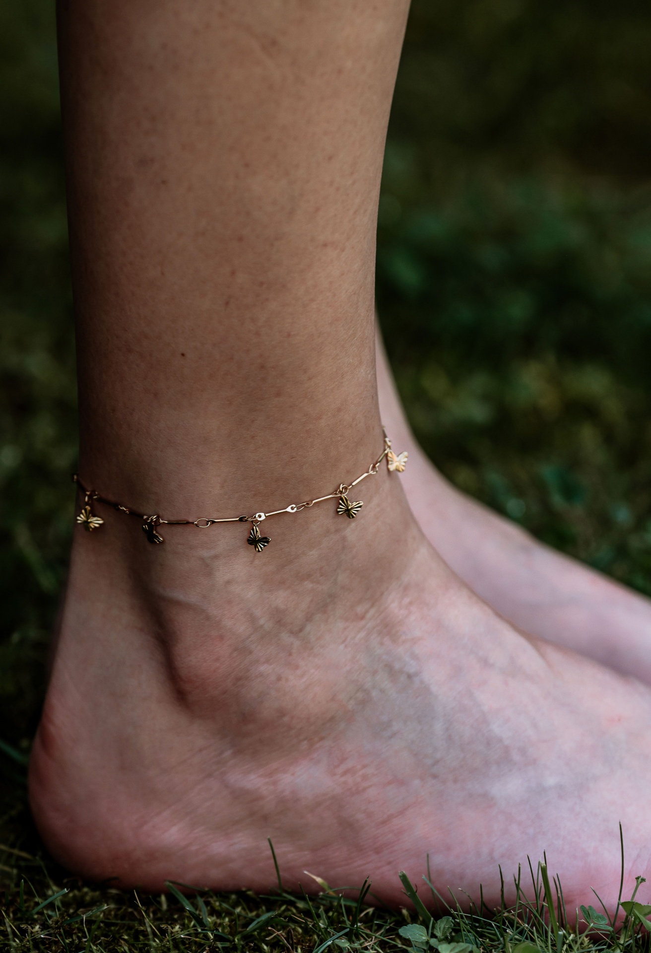 Tornozeleira dourada com pendentes em formato de abelha no tornozelo