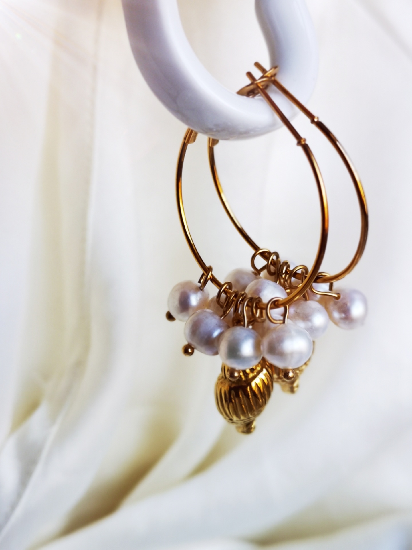 Brincos argola dourada com pérolas brancas e pingente dourado em suporte branco