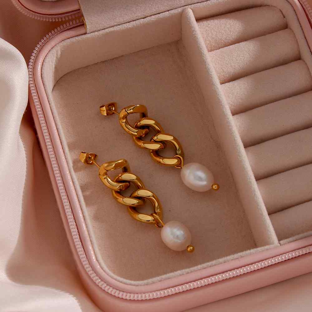 Brincos dourados com pérolas numa caixa de joias rosa