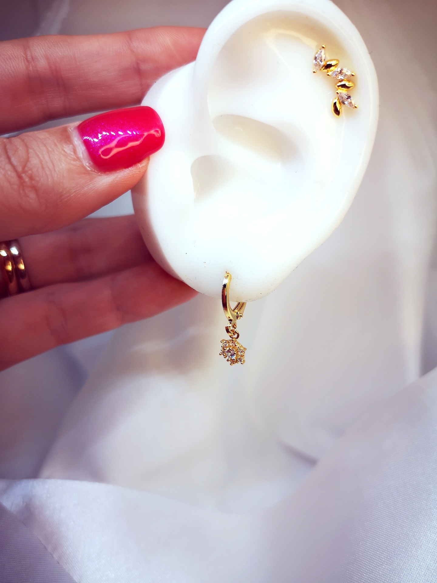 Modelo de orelha em silicone com brincos dourados e pedras brilhantes