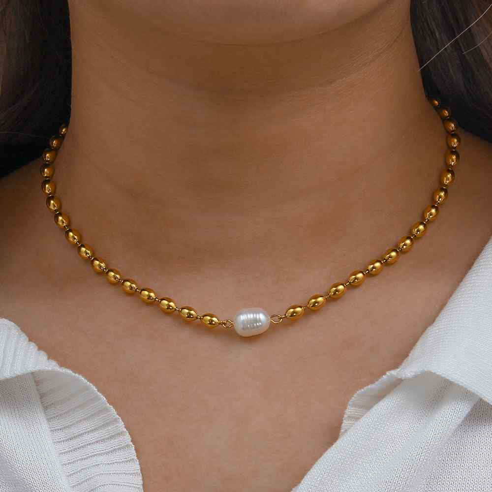 Colar dourado com pérola branca em pescoço feminino