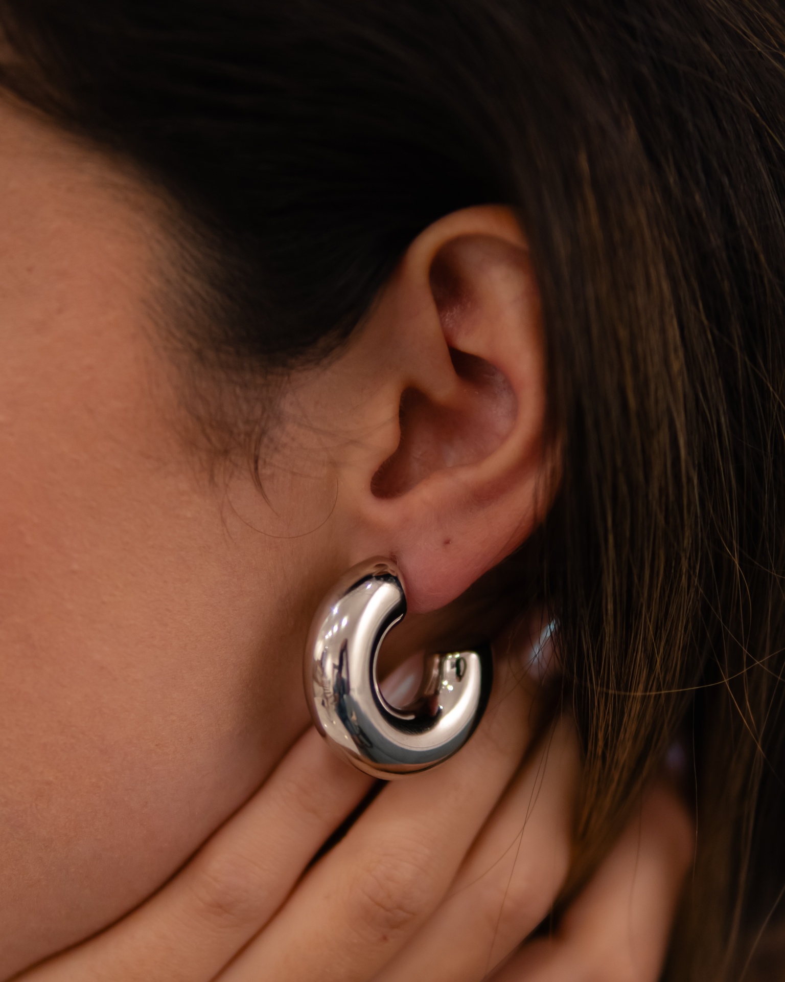 pendente argola grossa prateada num ouvido feminino