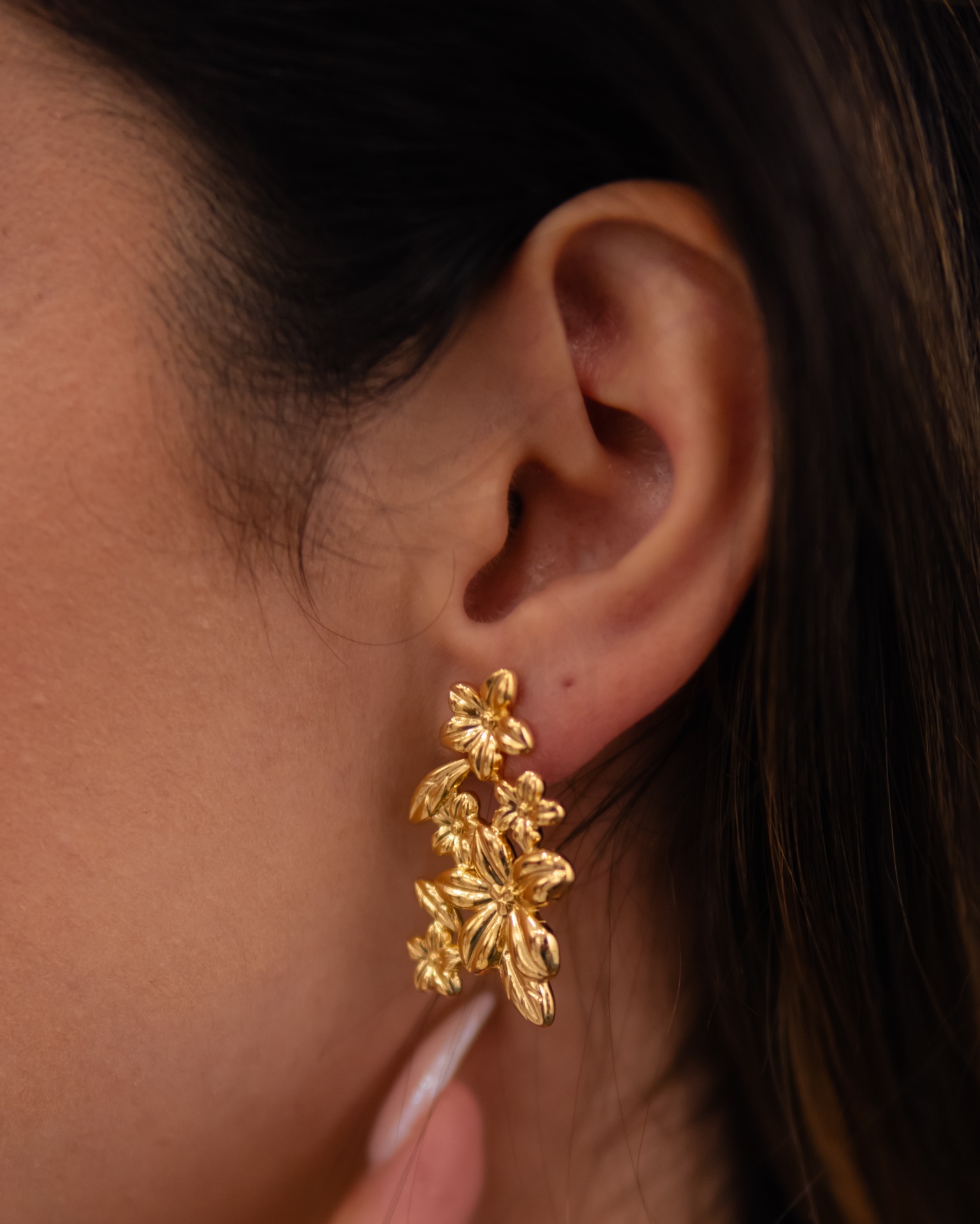 Brinco dourado com flores e folhas em orelha