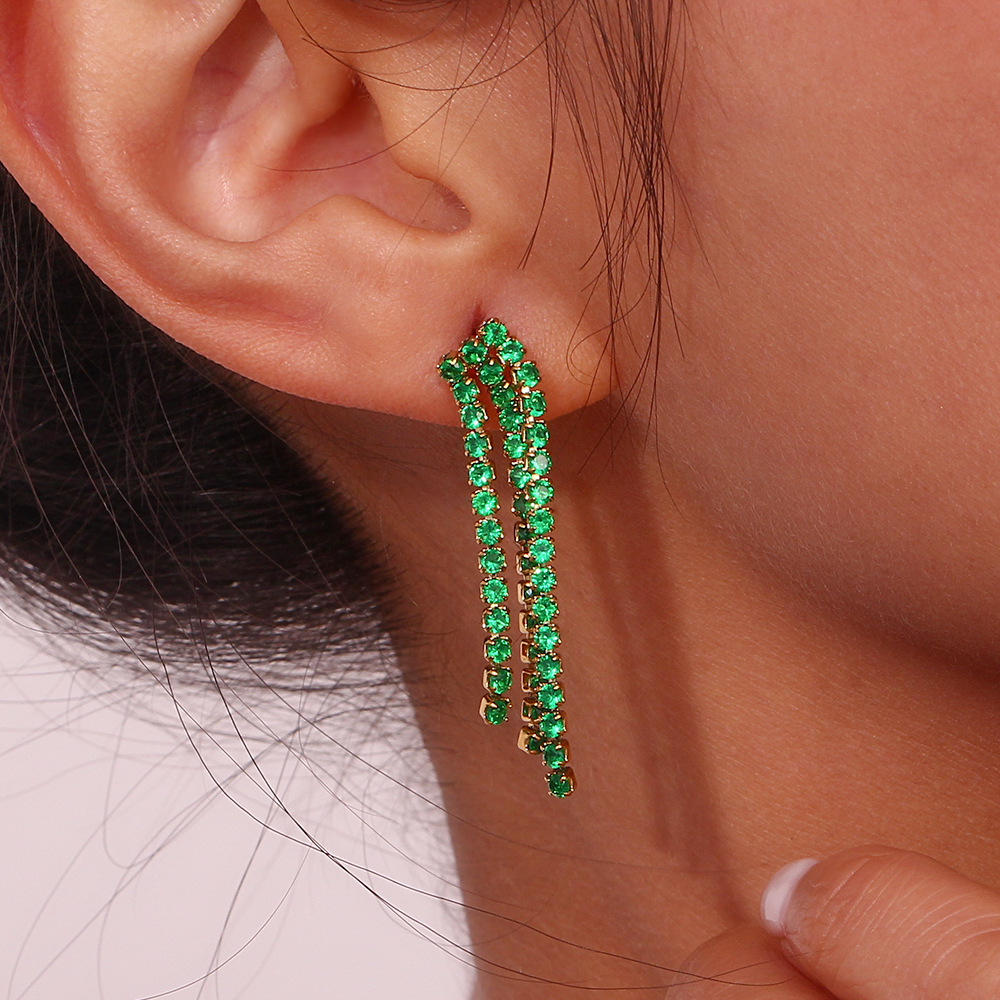 Brinco pendente com pedras verdes numa orelha feminina