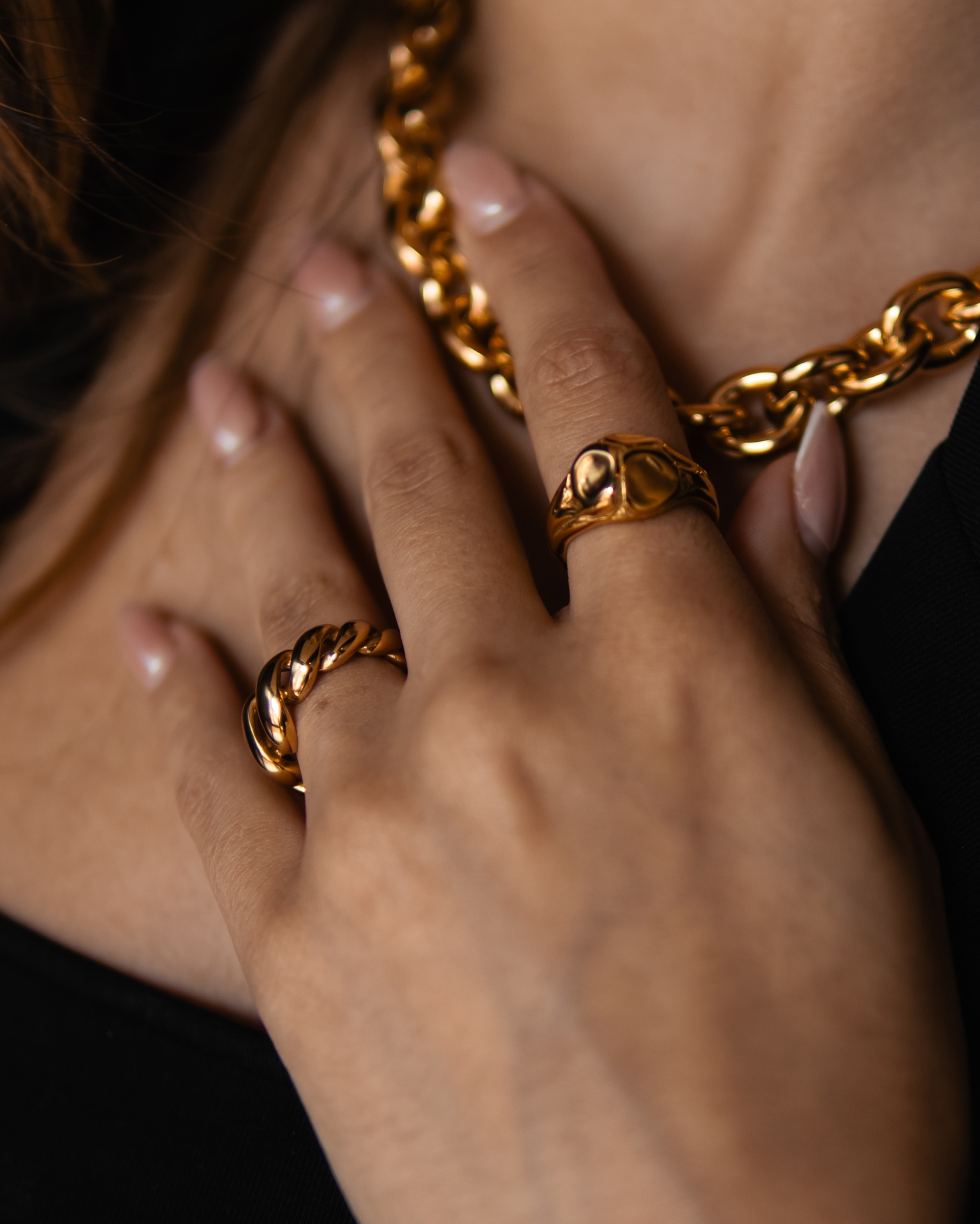 Colar e anéis dourados usados no pescoço e dedos com pele castanha clara