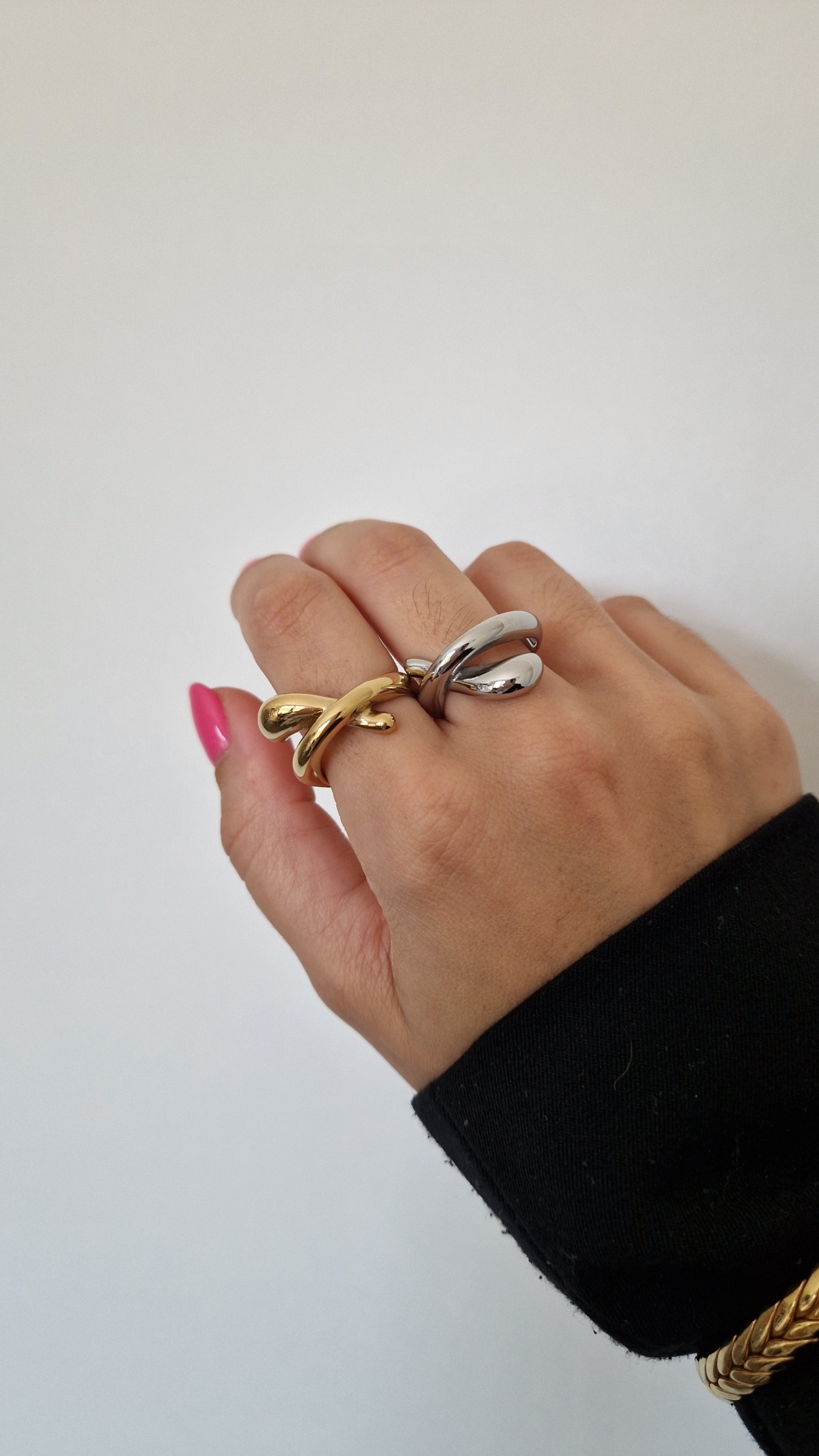 Mão a usar anéis dourado e prateado com fundo branco