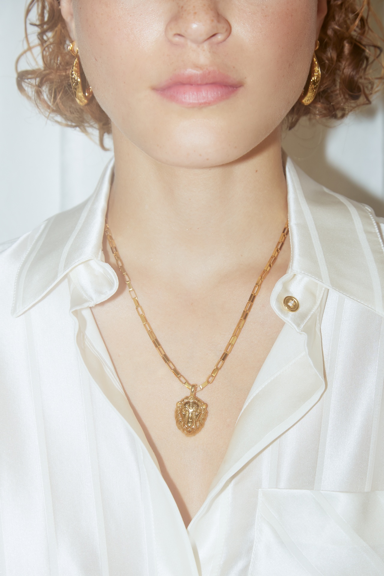 Colar e brincos de ouro usados com camisa branca