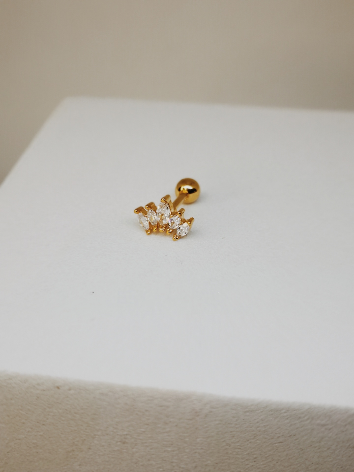 Brinco dourado com pedras cristal sobre superfície branca