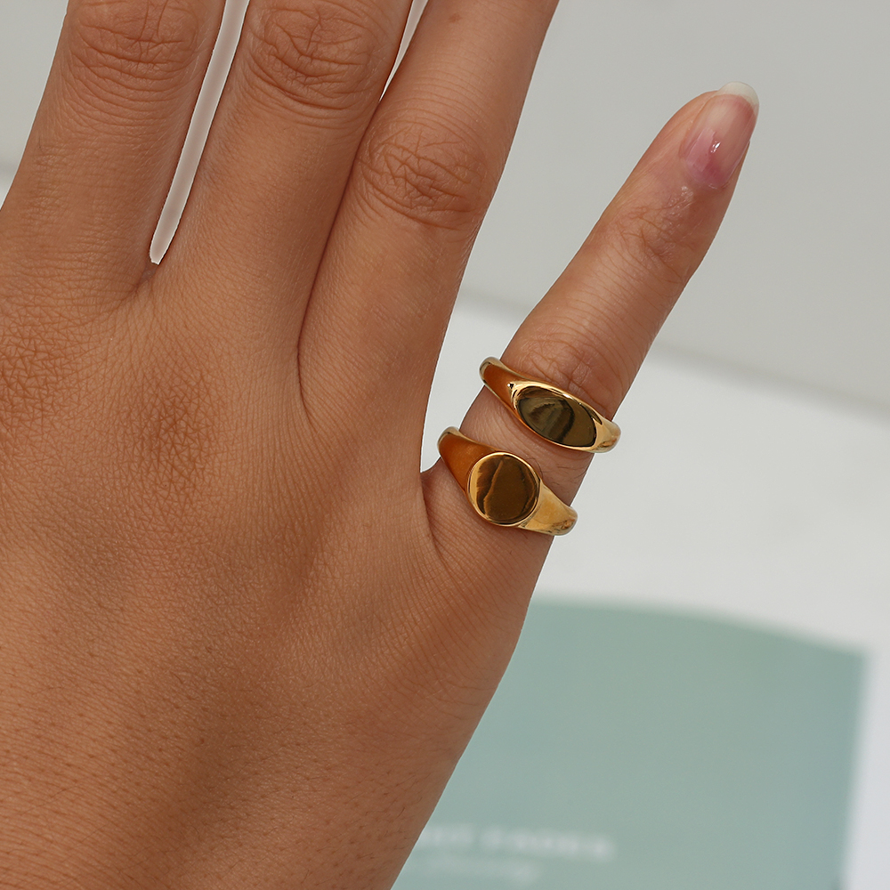 Mão com duas argolas douradas lisas e polidas em fundo desfocado