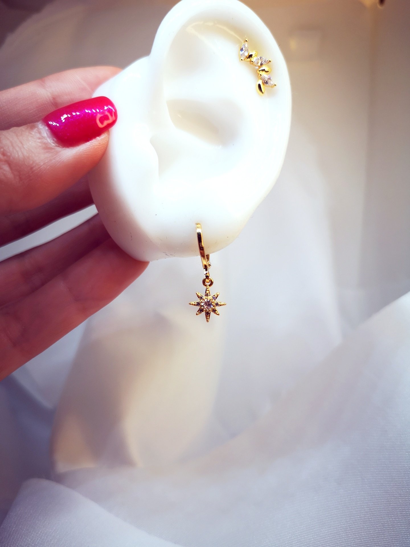 Brincos dourados com pedras brilhantes em orelha de manequim