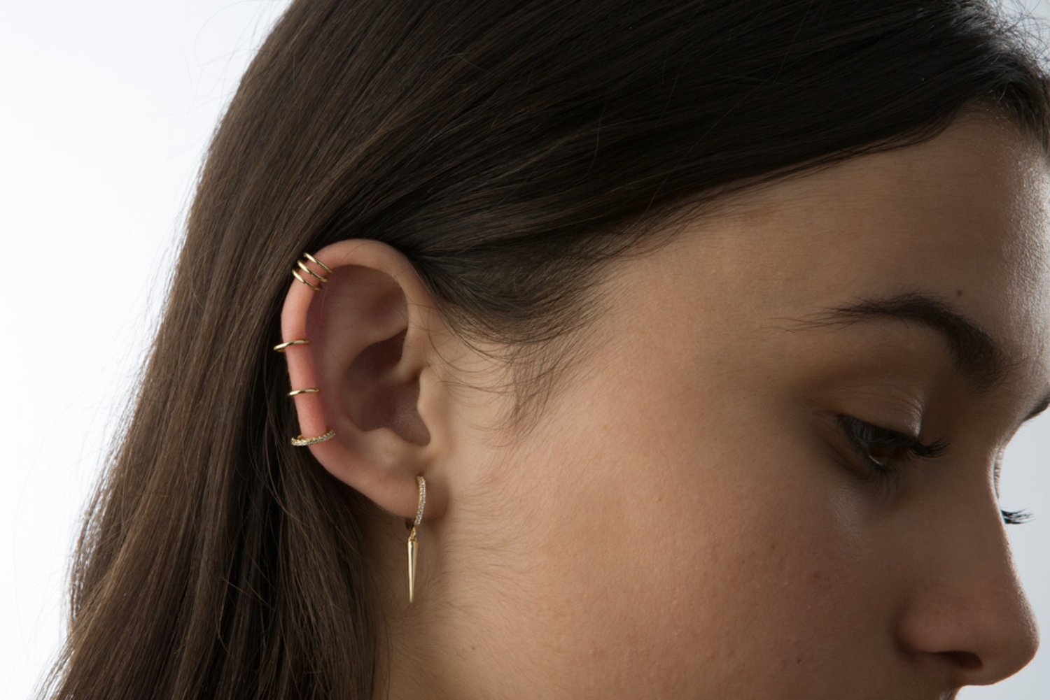 Mulher de perfil com brincos dourados na orelha esquerda