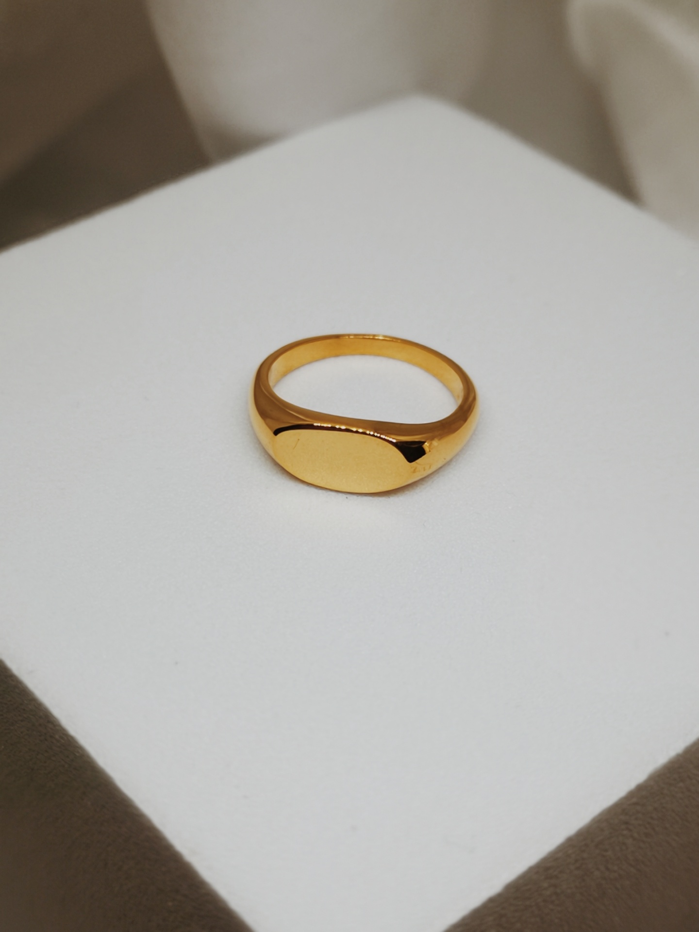 Anel dourado simples em base branca com fundo neutro