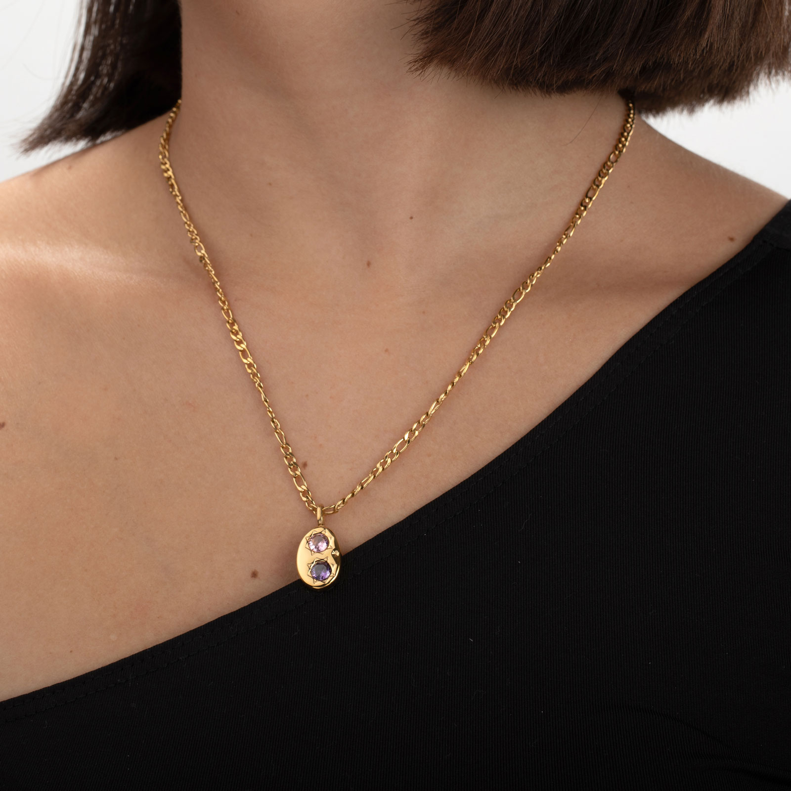 Colar dourado com pendente oval e duas pedras coloridas em pescoço feminino