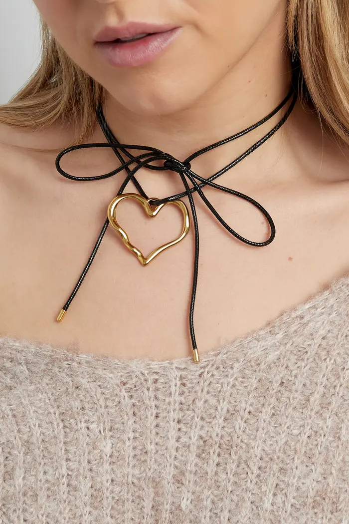 Colar choker preto com coração dourado na modelo com suéter bege