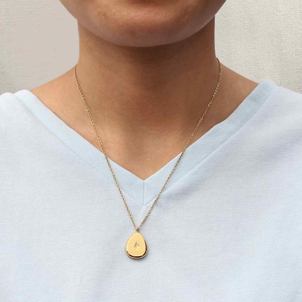 Colar dourado com pendente em gota mostrado numa pessoa com t-shirt branca