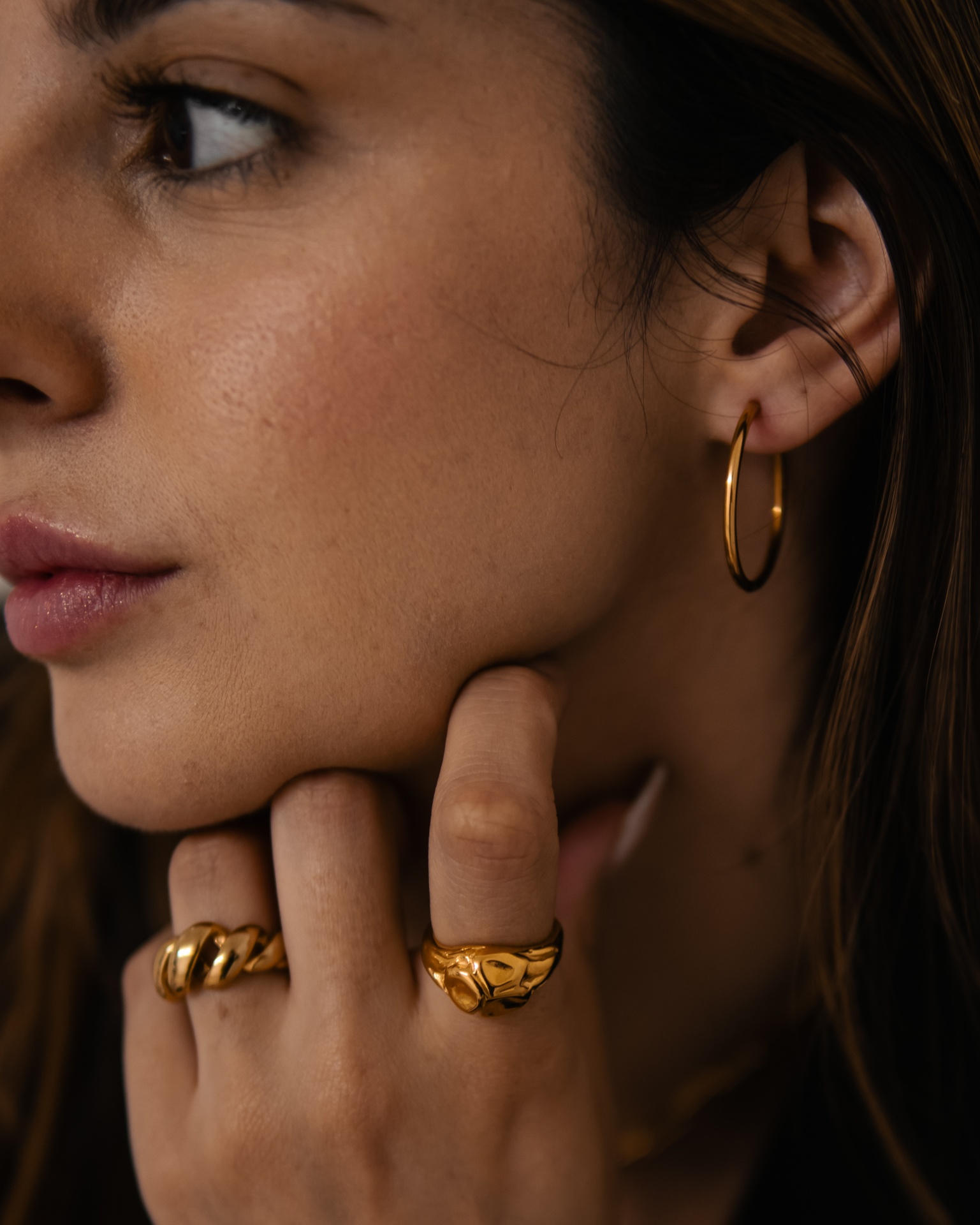 Mulher com brincos de argola e anéis dourados