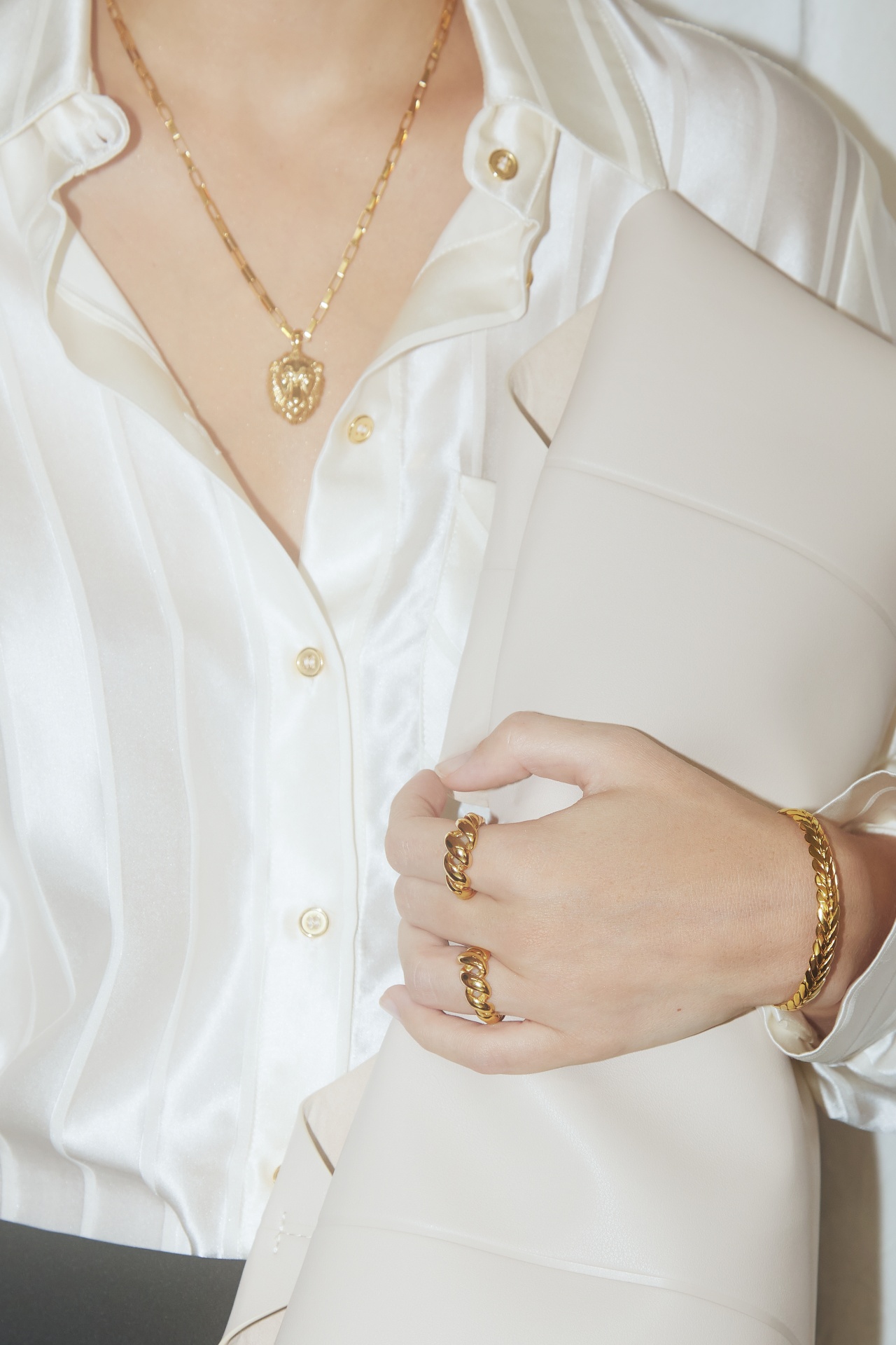 Blusa de cetim branca com joias douradas e bolsa bege claro