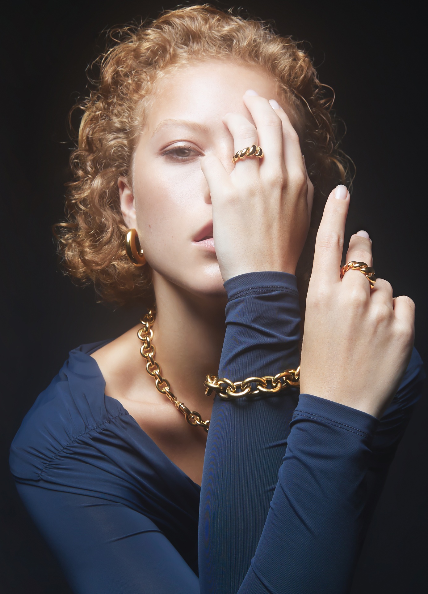Mulher com joias douradas e camisa azul escura