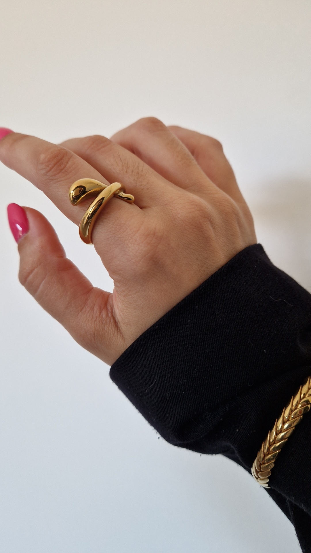 Mão feminina com anel e pulseira dourados em fundo branco