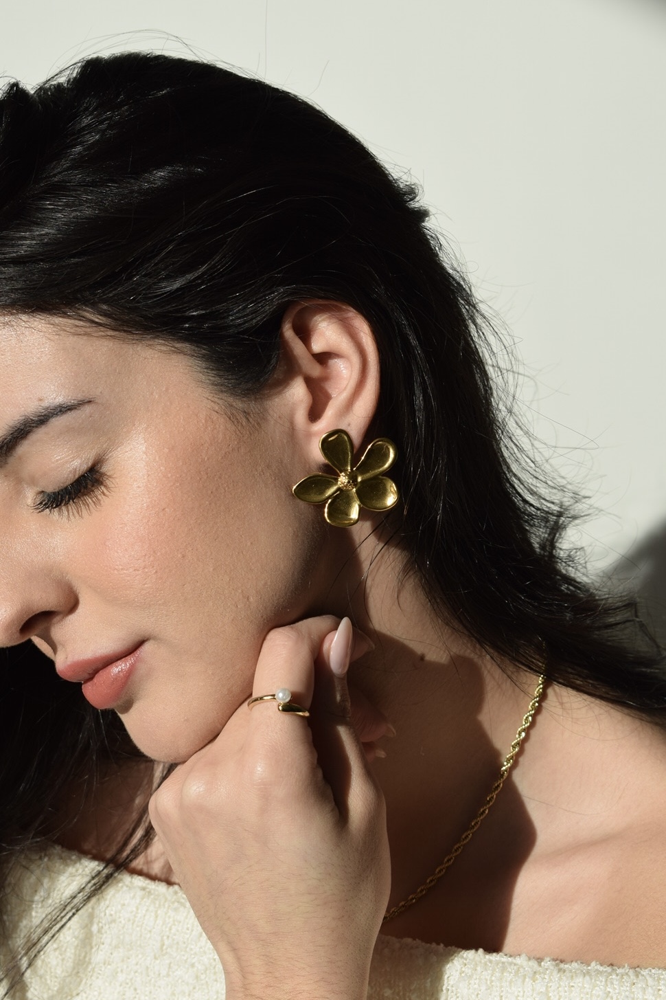 Mulher com brincos dourados em forma de flor e colar dourado