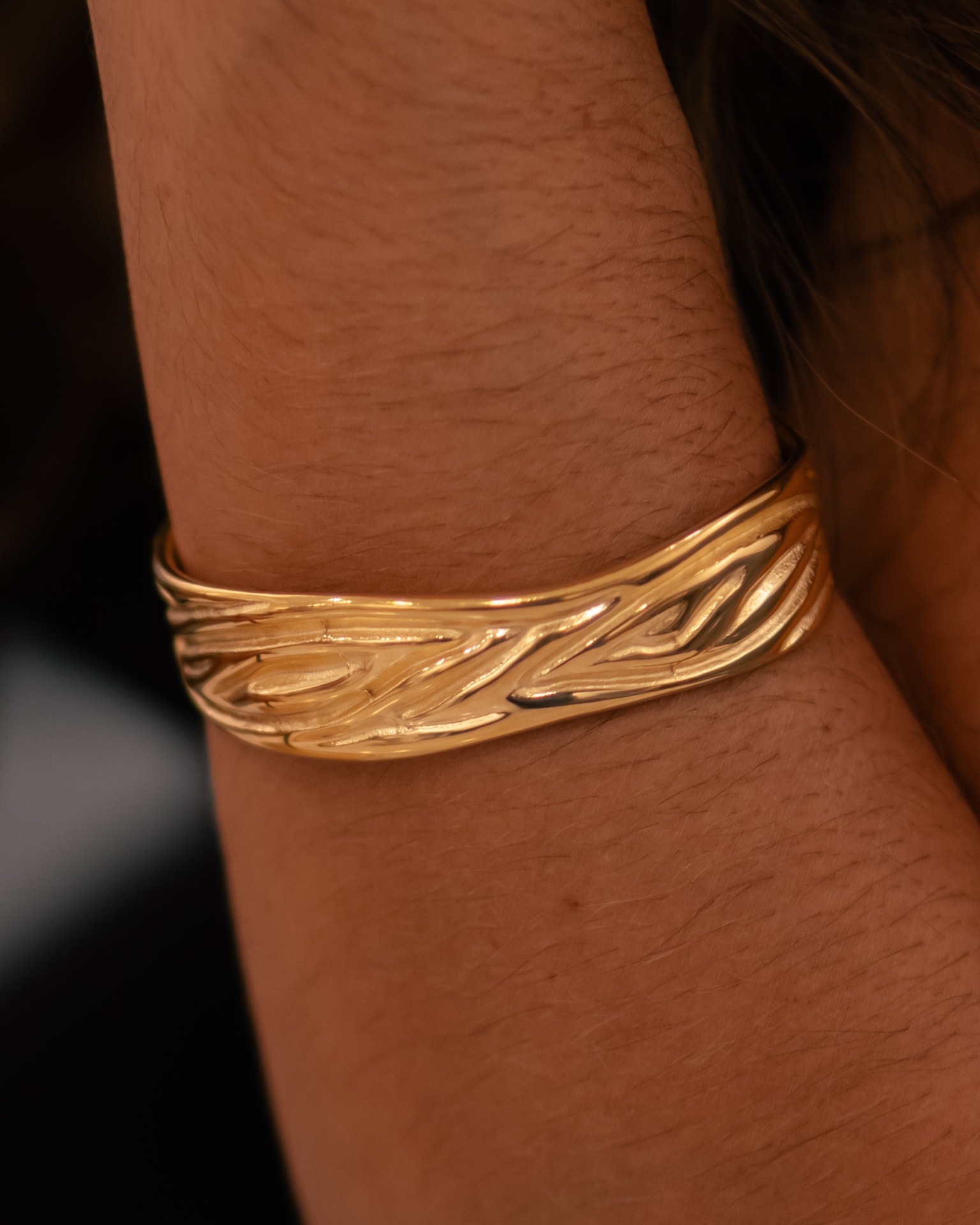 Bracelete dourado texturizado no pulso