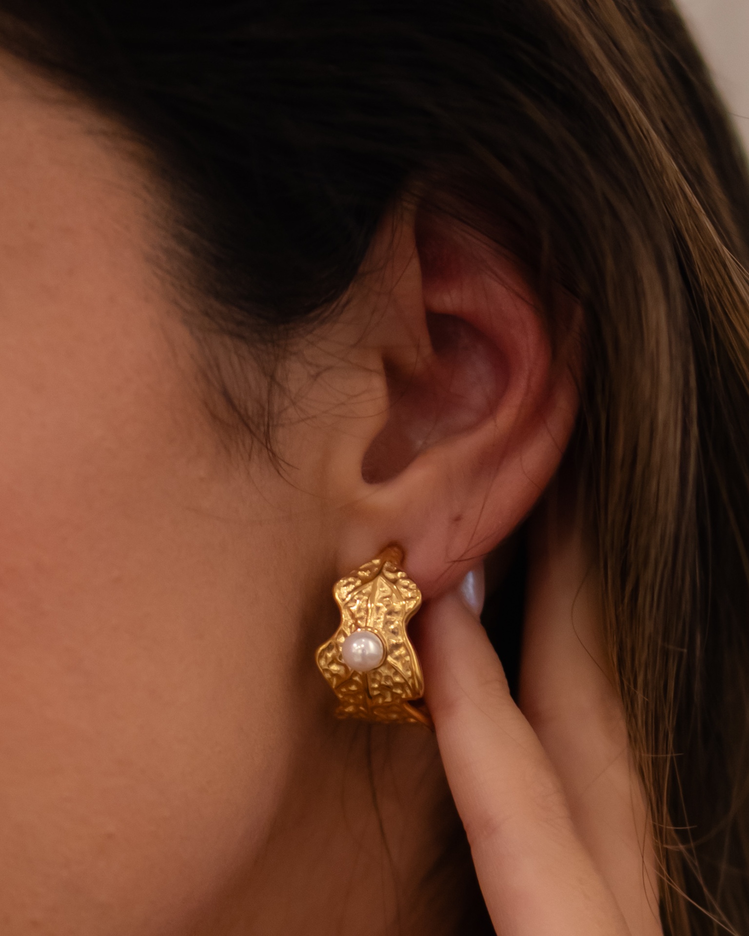 Brinco dourado texturizado com pérola na orelha