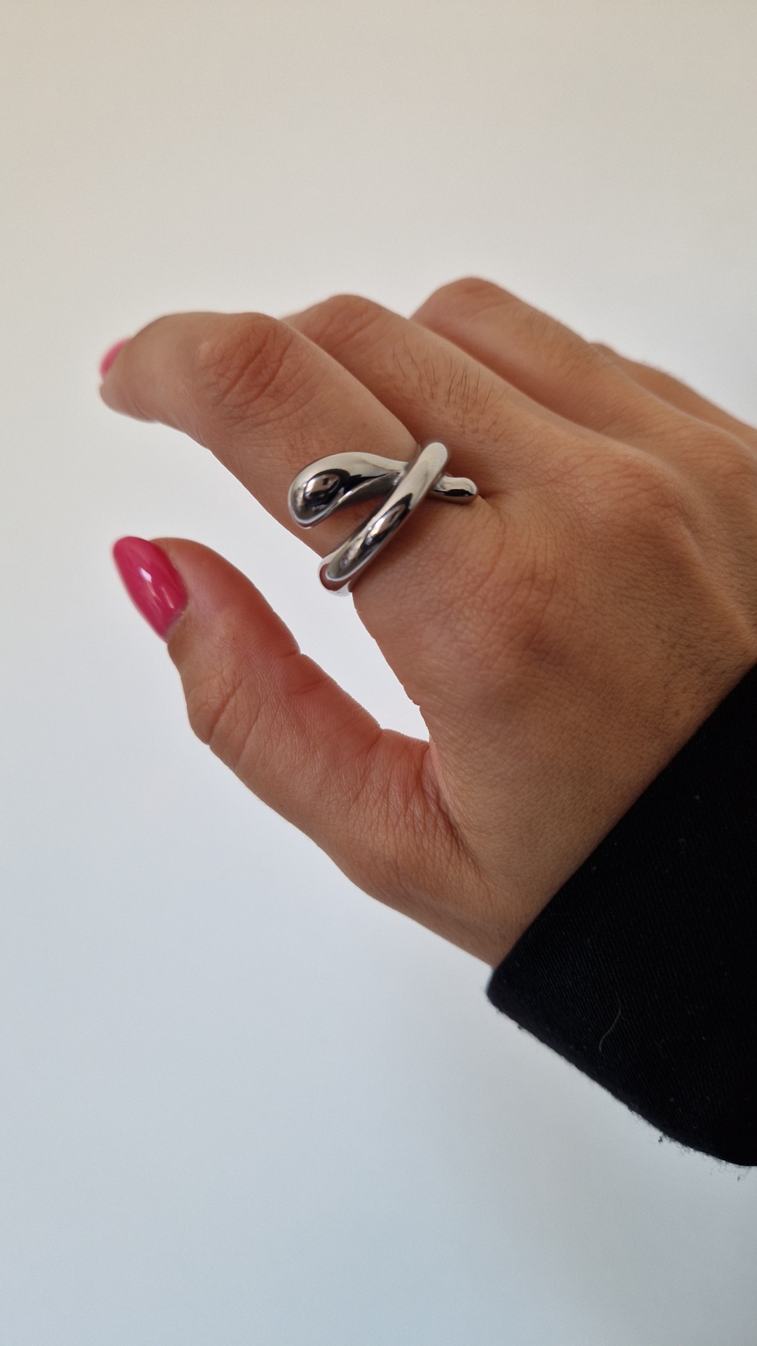 Anel espiral prateado no dedo médio com unhas cor de rosa