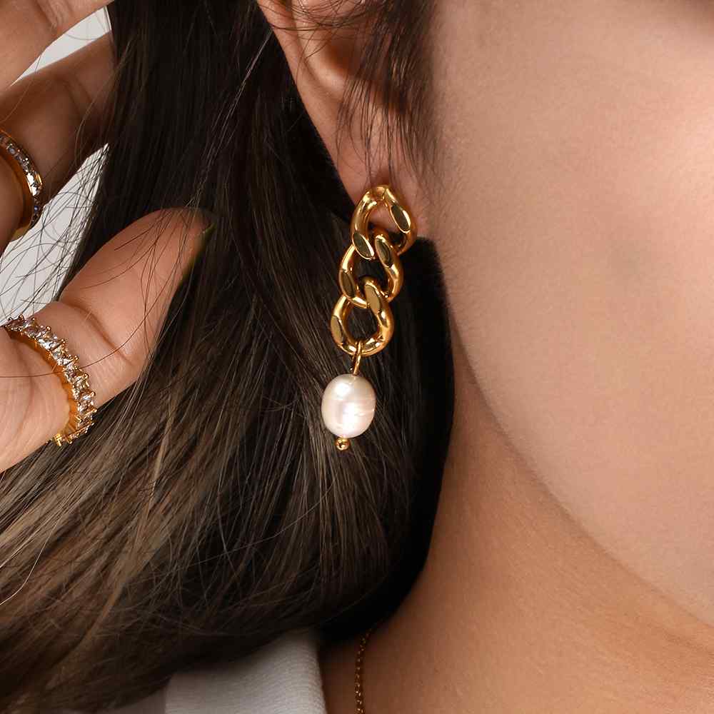 Brinco dourado com elos e pérola pendurada na orelha